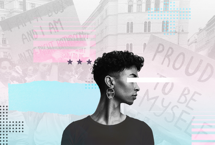 A person is standing against LGBTQIA activist signs.