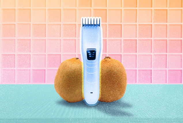 two kiwis with fuzzy skin on either side of silver cordless electric clipper on orange and pink gradient tile background