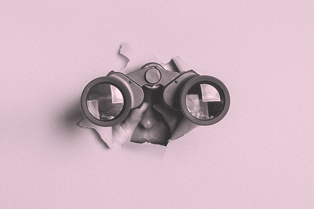A pair of binoculars bust through a pink wall with someone looking through them.