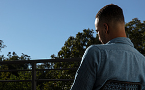 Man-sits-in-chair-facing-away-from-camera