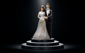 A bride and groom cake topper sits on a tiered pedestal with a spotlight lighting the couple from above.