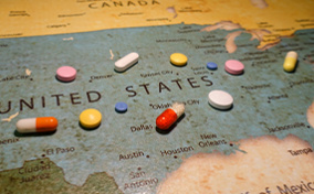 Pills are scattered over a map of the US.