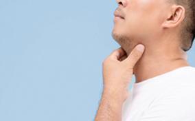A man holds his hand along his throat to check his glands.