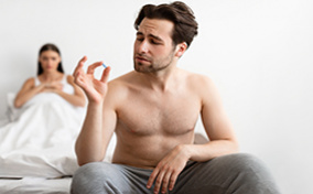 A man sitting on a bed holds up a prescription drug that could cause a low sex drive.