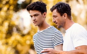 A father walks with his son having a discussion about consent.